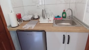 Cocina compacta con lavavajillas, un lavabo y una encimera con varios utensilios de cocina.