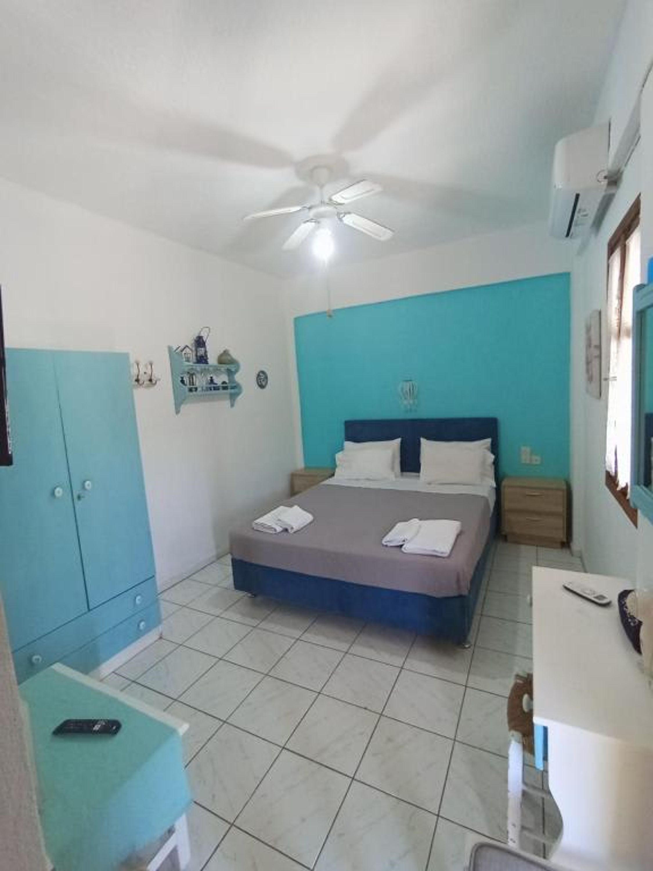 A bedroom with a bed, a wardrobe, a desk, and a ceiling fan.