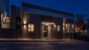 A modern building with a well-lit entrance, a visible door, and a small window. - Green Blue Castella Luxury Suites Saronic Pearl (Piraeus)