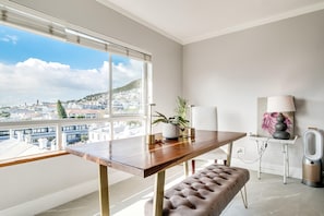 Ein modernes Zimmer mit einem Holztisch, einer Bank, einem Blumentopf, einer Lampe und einem Lautsprecher.