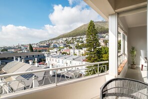 Ein Balkon mit Blick auf ein Wohngebiet, einer Kübelpflanze und einem Korbstuhl.
