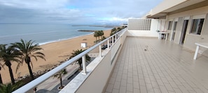 Ein Balkon mit Blick auf Strand und Meer, ein Fliesenboden und ein GelÀnder.