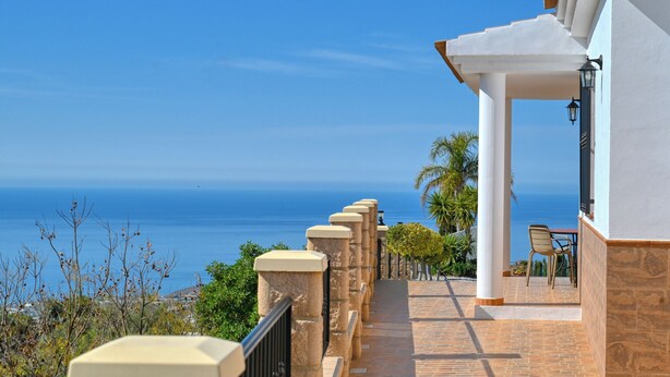 A coastal walkway with a view of the sea, a covered outdoor seating area, and a building with a white facade. - Kousgaard - Spacious private villa in quiet area with pool and sea view (Sayalonga)