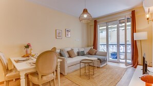 Ett modernt vardagsrum med en soffa, ett matbord, stolar, ett litet soffbord och en balkong med utsikt.