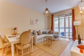 A modern living room with a sofa, dining table, chairs, a small coffee table, and a balcony with a view. - L'Orangeraie AP4506 by Riviera Holiday Homes (Nice)