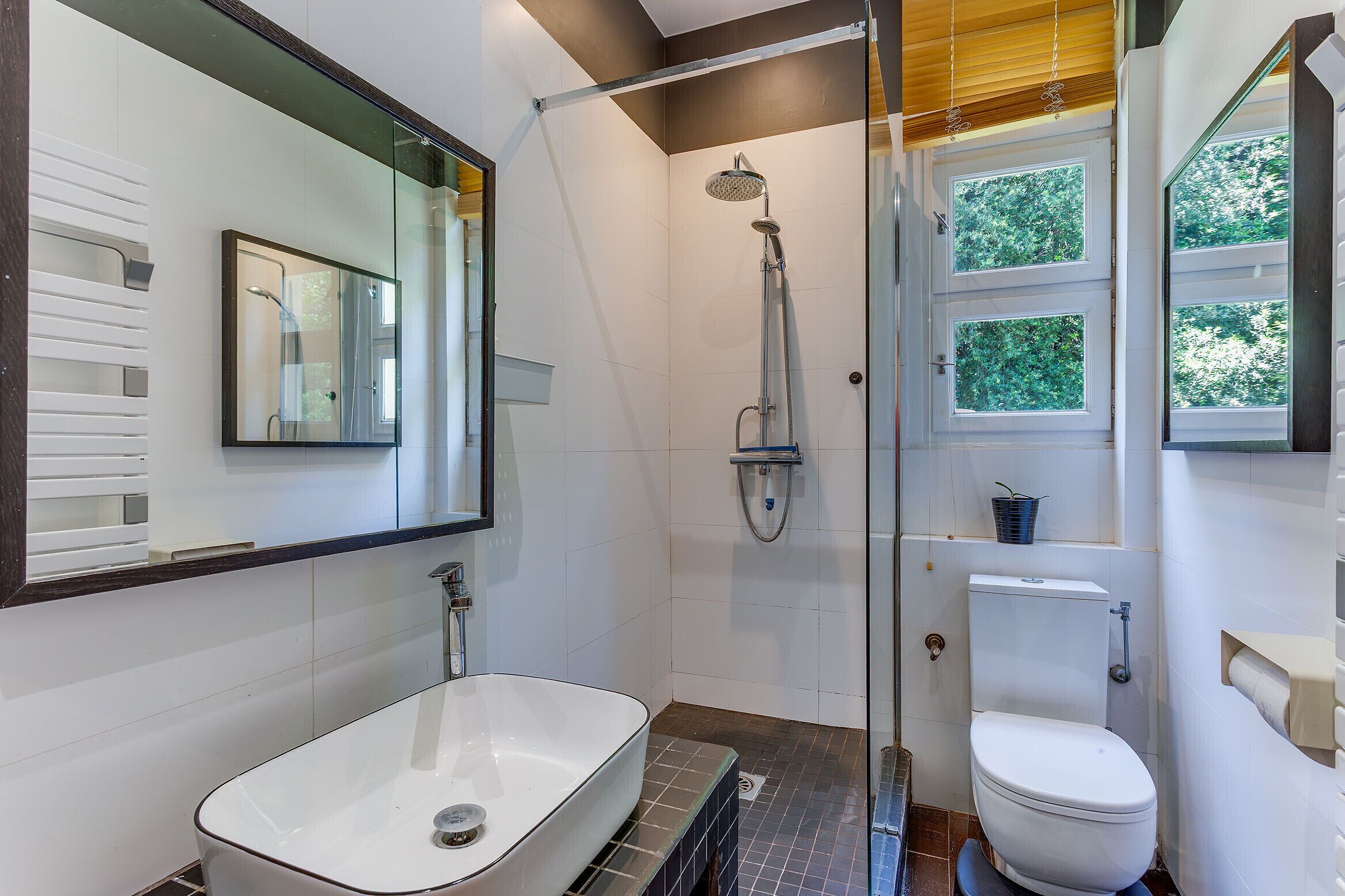 Ein modernes Badezimmer mit einer Duschkabine aus Glas, einem weißen Waschbecken und einer Toilette.