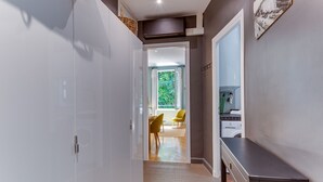 En hall som leder till en matplats med stolar, ett bord och utsikt över grönområden utanför.
