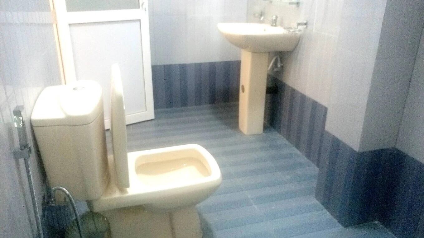 A bathroom with a toilet, sink, and striped floor tiles.