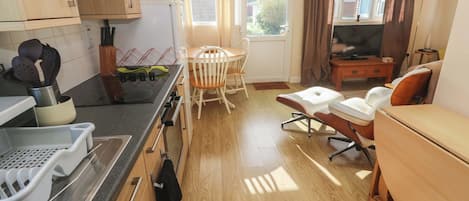 A compact kitchen with a dining area, a TV, and a window with curtains.