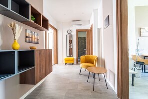 A modern interior with a sofa, a small table, a clock, and a mirror on the wall. - GuestHost - Modern Flat X4 near the Center (Trieste)