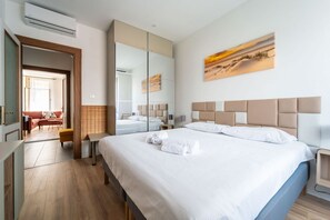 A hotel room with a large bed, a mirror, a painting, and a wooden floor. - GuestHost - Modern Flat X4 near the Center (Trieste)