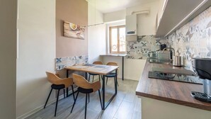A compact kitchen with a dining area, a small window, and a tiled backsplash. - GuestHost - Modern Flat X4 near the Center (Trieste)