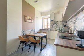 A compact kitchen with a dining area, a small window, and a tiled backsplash. - GuestHost - Modern Flat X4 near the Center (Trieste)