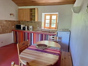 Eine Küche mit gestreiftem Tischläufer, Holzschränken, einer Mikrowelle und einem Kühlschrank.
