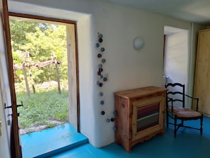 Ein Zimmer mit einem Holzkasten, einem Sessel, einer Wandleuchte und einer Tür zu einem Außenbereich.