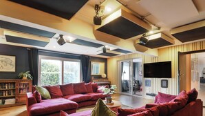 Een woonkamer met een rode bank, een boekenkast, een flatscreen-tv en een schuifpui naar een balkon.
