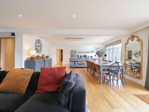 A modern living room with a dark sofa, a dining area with wooden chairs, and a kitchen in the background. - Denmark House (Chatham)