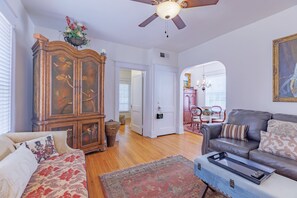 A living room with a sofa, a coffee table, a cabinet, and a ceiling fan.
