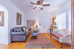 A living room with a ceiling fan, a sofa, a loveseat, a rug, a side table, and a lamp.