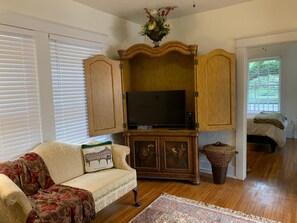 A living room with a sofa, television, wooden cabinet, and a decorative basket.
