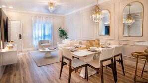 A modern dining area with a white table set for four, wooden flooring, and a chandelier. - Disney 3BR Villa in Lucaya Harbor Resort (Kisssimmee)