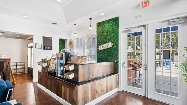 A bakery counter with a sign, a reception desk, and a view of the outdoor seating area. - Disney 3BR Villa in Lucaya Harbor Resort (Kisssimmee)