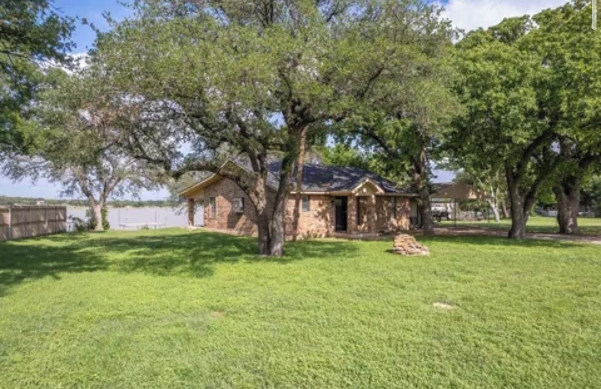 A house with a stone exterior, a wooden deck, and a lawn.