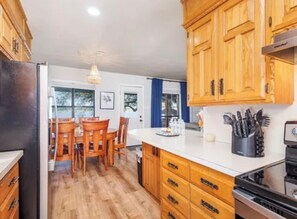 A kitchen with wooden cabinets, a central island, and a dining area with chairs.