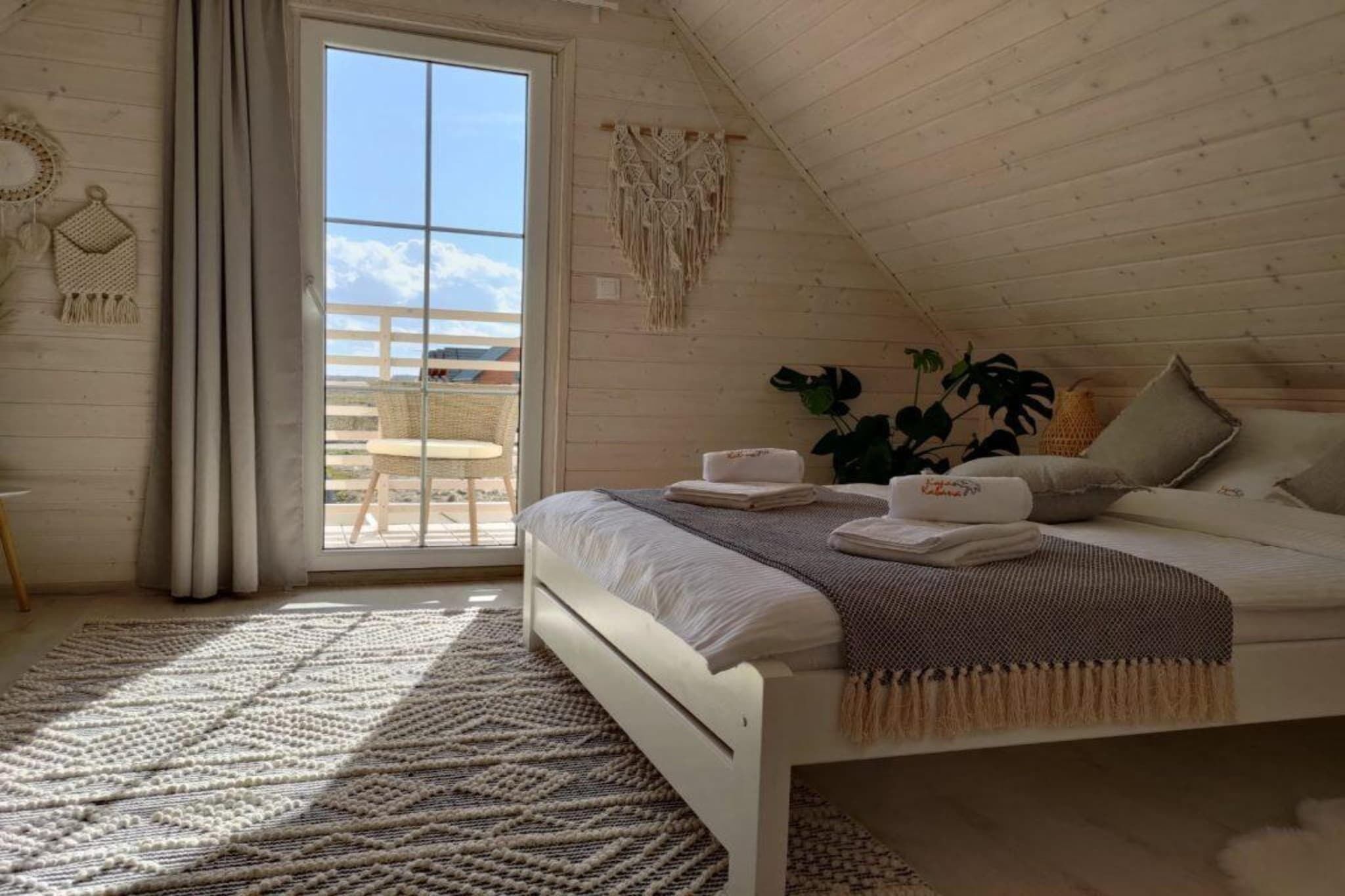 Une chambre à coucher avec un lit, une fenêtre, une vue sur l’extérieur et une plante.