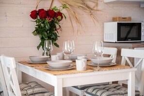 A dining table set with plates, bowls, and wine glasses, with a vase of red roses on the wall behind. - Holiday home with terrace, garden, and pool (Kopan)