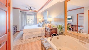 A hotel room with a large bed, a bathroom with a bathtub, a ceiling fan, and a large mirror. - 2 bdrm Ski in/Ski out Westgate Resort in Beautiful Park City (Park City)