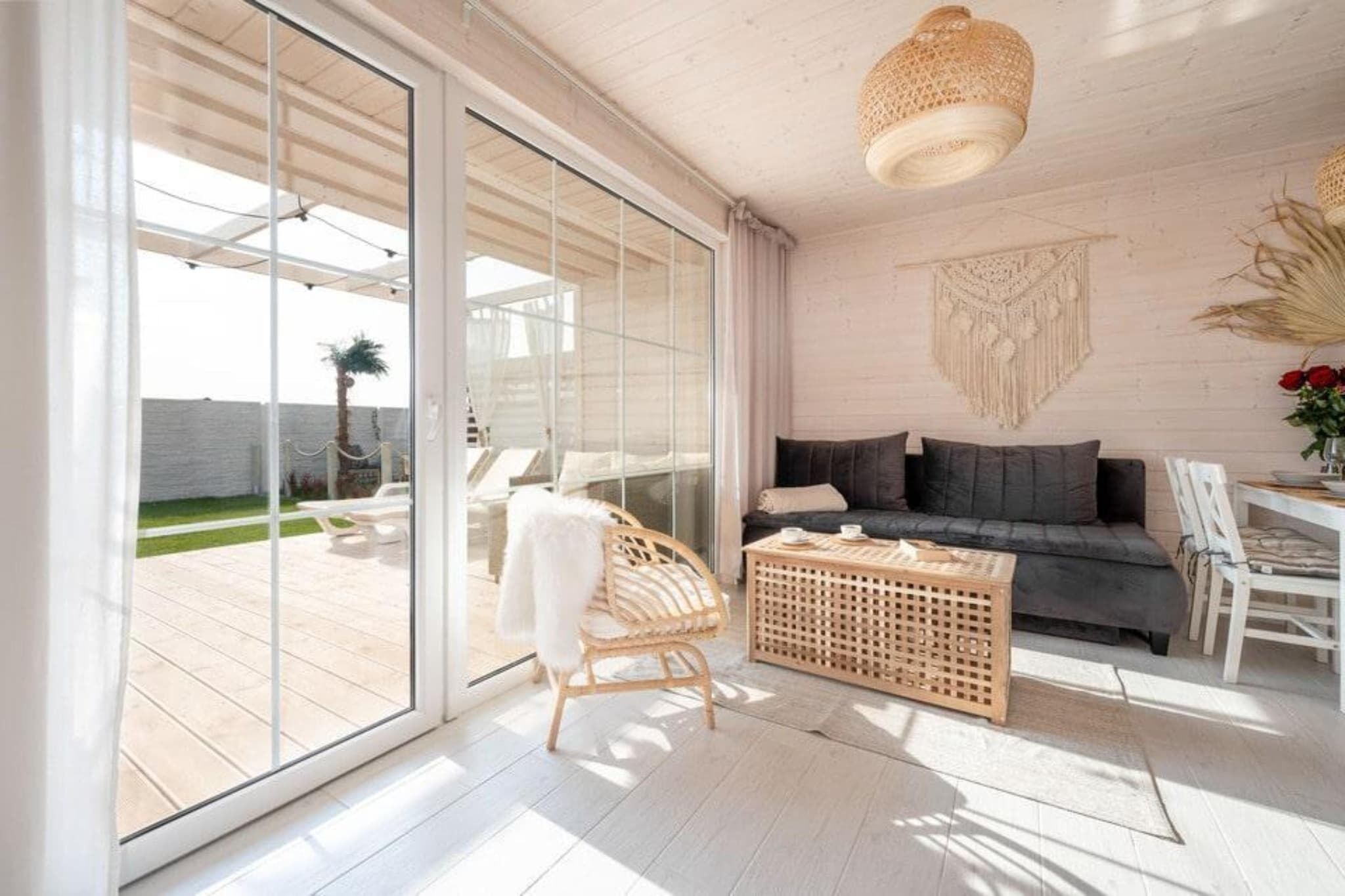 Et moderne interiør med en sofa, en fletstol, et sofabord og en dekorativ vægpynt.