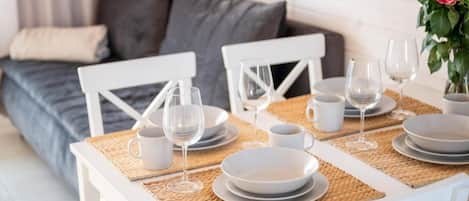 A dining table set with white plates, glasses, and a white mug, placed on a woven placemat.