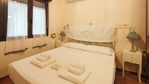 A neatly made bed with rolled towels, a bedside lamp, and a wall-mounted air conditioner. - Incanto Retreat with Terrace – Golfo Aranci (Punta Pedrosa)