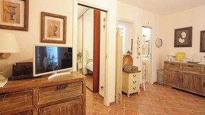 A room with a television on a wooden dresser, a door leading to another room, and a cabinet with drawers. - Incanto Retreat with Terrace – Golfo Aranci (Punta Pedrosa)