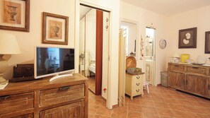 Une pièce avec un téléviseur posé sur une commode en bois, une porte donnant sur une autre pièce et un meuble avec des tiroirs.