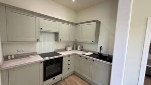 A compact kitchen with a built-in oven, a sink, and a toaster. - Holt Hall - Ground Floor Apartment (Matlock)