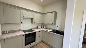 A compact kitchen with a built-in oven, a sink, and a toaster. - Holt Hall - Ground Floor Apartment (Matlock)