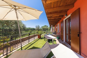 A balcony with a table, chairs, and a large umbrella.