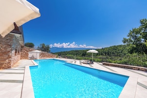 A swimming pool with a stone wall and a view of the mountains.