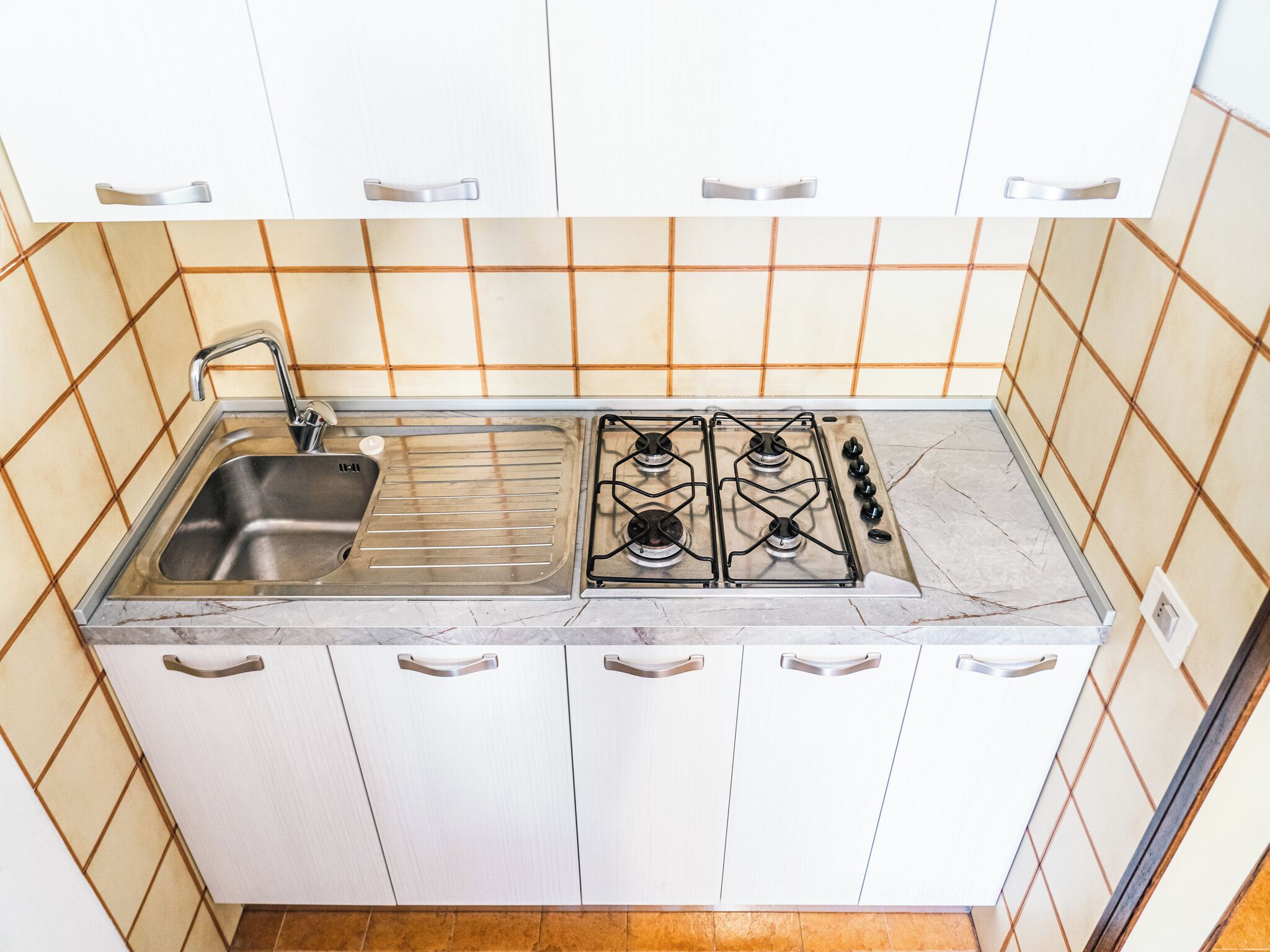 A kitchen with a sink, stove, and white cabinets.