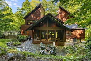 Eine zweistöckige Blockhütte mit überdachter Veranda und Sitzbereich im Freien.