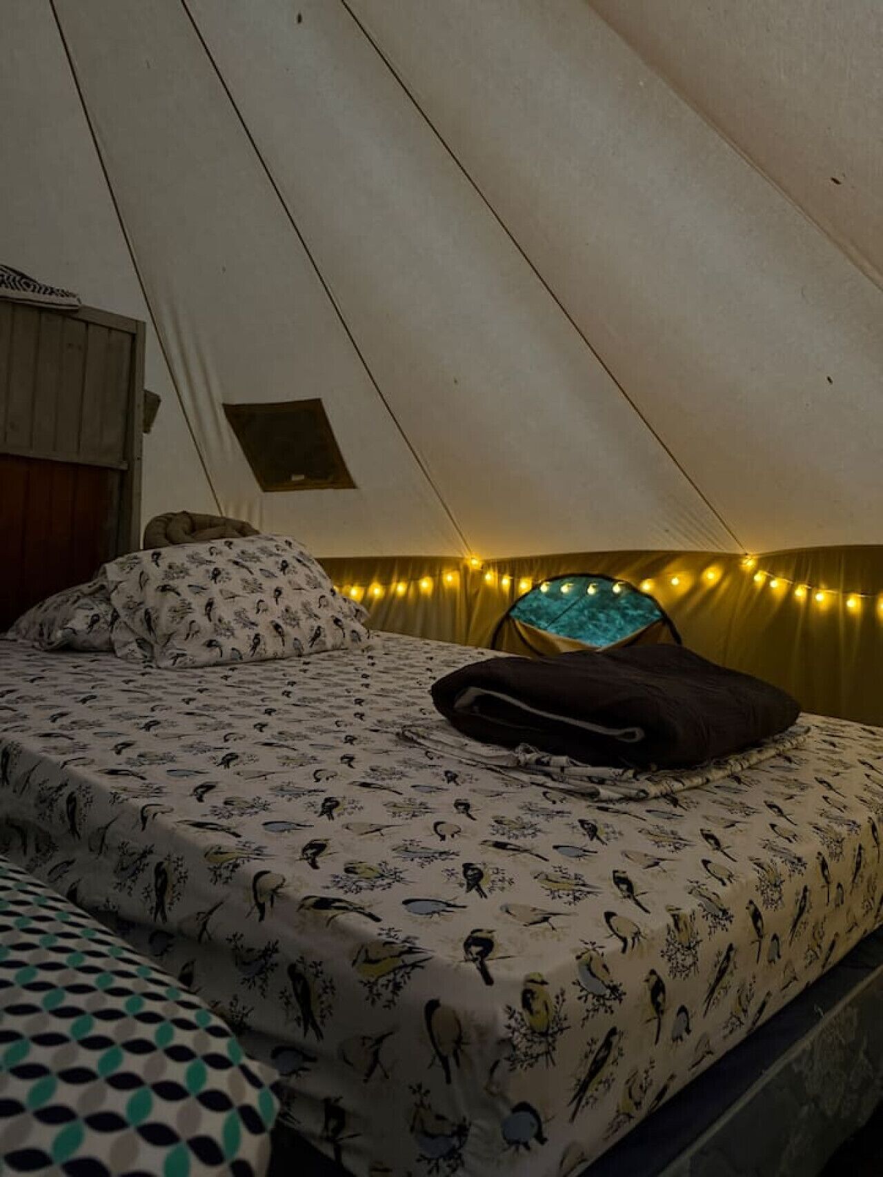 Una carpa con cama, almohadas y luces de cadena.