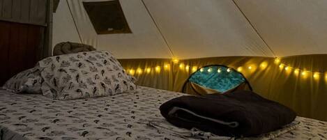 Una carpa con cama, almohadas y luces de cadena.