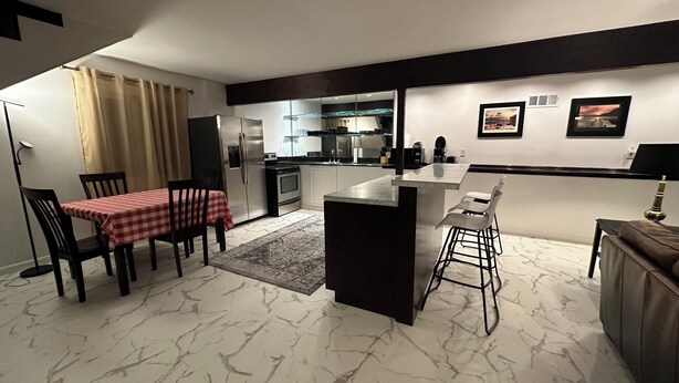Una cocina moderna con comedor, una barra pequeña y un espacio de sala.
