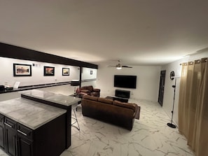 A modern living room with a sofa, a flat-screen TV, and a ceiling fan.