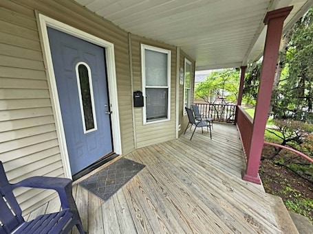 A covered porch with a door, windows, and a chair.. Dayton Dorm Style House 3-51