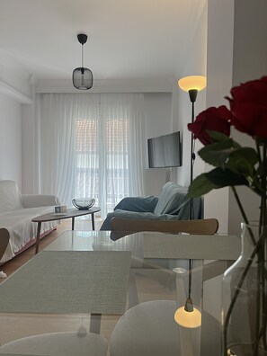 Ein modernes Wohnzimmer mit einer Couch, einem Couchtisch und einem an der Wand befestigten Fernseher.
