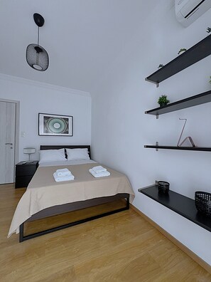 Ein modernes Schlafzimmer mit einem Bett, Nachttischen, einer Pendelleuchte und eingebauten Regalen.