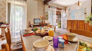 Un comedor con una mesa dispuesta para el desayuno, incluyendo tazones, platos y una cesta de frutas.